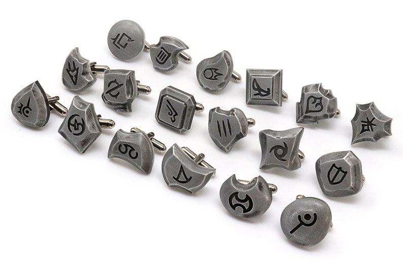 May include: A set of 18 silver cufflinks with different symbols, including a crescent moon, a star, a shield, and a sword.