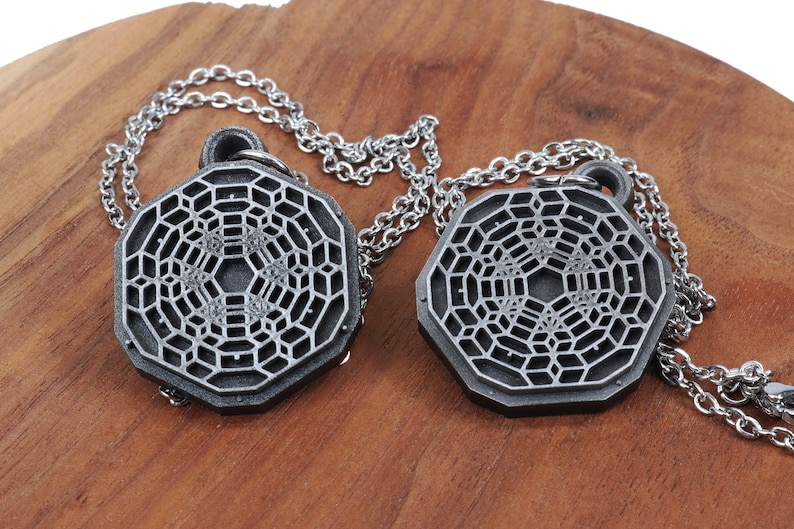 May include: Two silver necklaces with geometric pendant charms. The pendants are octagonal and feature a detailed, intricate design.