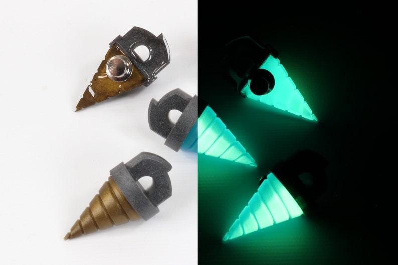 May include: A split image shows three drill-shaped objects. On the left, the objects are gold and gray, with a metallic button. On the right, the objects glow bright teal. The objects have a gray top with a hole.