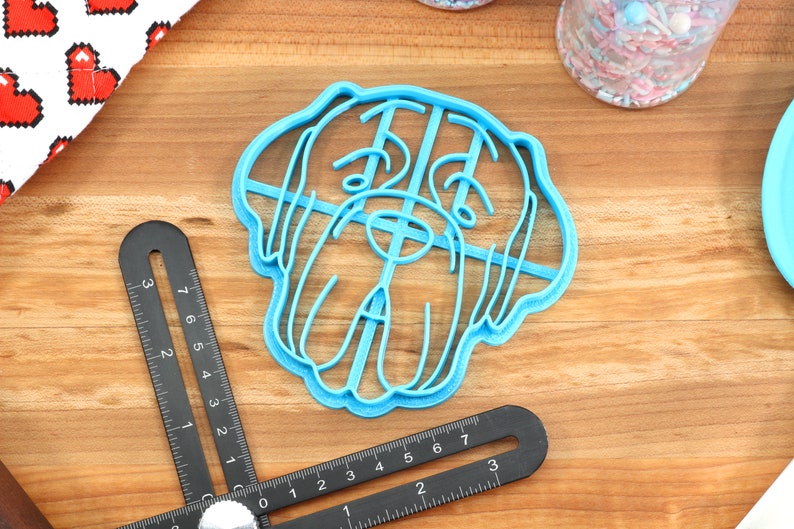 Peut inclure: Emporte-pi&egrave;ce en plastique bleu en forme de t&ecirc;te de chien. L'emporte-pi&egrave;ce a un design d&eacute;taill&eacute; avec des lignes et des courbes.