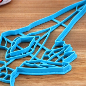 May include: A blue plastic cookie cutter shaped like a rocket ship with a detailed design. The cutter has multiple layers, creating a 3D effect.