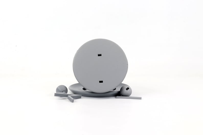Pode incluir: Uma base de pl&aacute;stico cinza com dois orif&iacute;cios, um suporte de pl&aacute;stico cinza com uma pequena bola de pl&aacute;stico cinza em cada extremidade e uma figura de pl&aacute;stico cinza em forma de estrela.