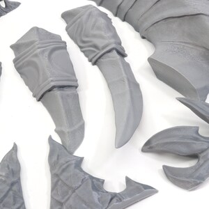 Pode incluir: Um conjunto de pe&ccedil;as de pl&aacute;stico cinzento impressas em 3D para uma figura em miniatura. As pe&ccedil;as incluem um par de bra&ccedil;os, um par de pernas, uma cauda, um par de asas e uma cabe&ccedil;a.