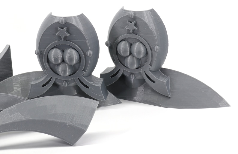 May include: Two gray 3D printed decorative pieces with a star and three circles design. The pieces are on a white surface.