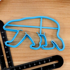 May include: A light blue plastic cookie cutter shaped like a polar bear. The cutter is about 6 inches long and 4 inches wide.