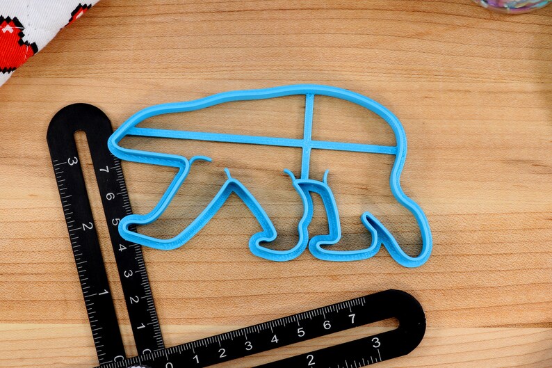 May include: A light blue plastic cookie cutter shaped like a polar bear. The cutter is about 6 inches long and 4 inches wide.