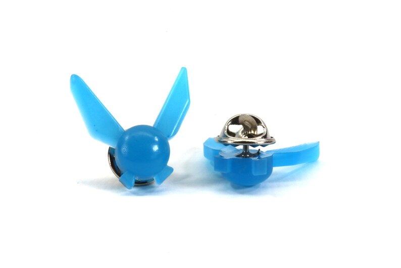 Peut inclure: Une &eacute;pingle en plastique bleue avec un motif du symbole Triforce de la s&eacute;rie de jeux vid&eacute;o The Legend of Zelda. L'&eacute;pingle a un fermoir m&eacute;tallique au dos.