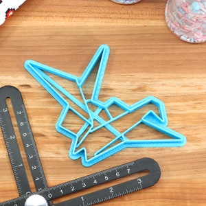 May include: A light blue plastic cookie cutter shaped like an origami crane.
