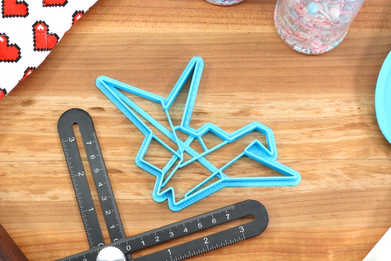 May include: A light blue plastic cookie cutter shaped like an origami crane.