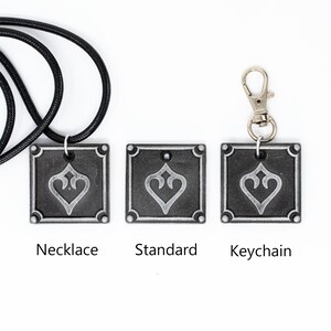 May include: Three versions of a silver-colored pendant with a stylized heart design. The pendant is available as a necklace, keychain, or standard pendant.