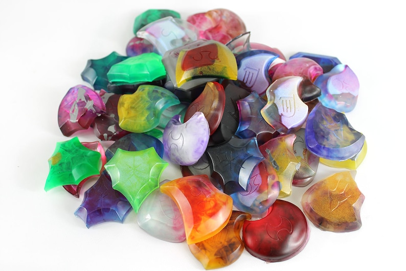 May include: A collection of colorful, translucent, resin game pieces in various shapes, including stars and crescent moons. Each piece features a unique design and intricate details.