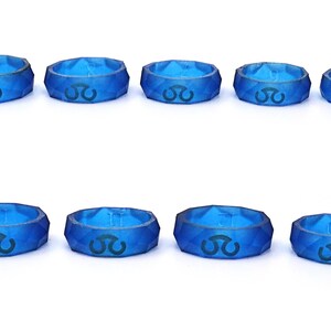 May include: Ten blue silicone rings with a geometric design and a black symbol on each ring.