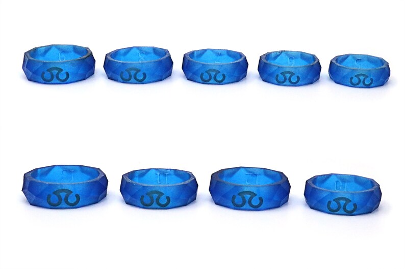May include: Ten blue silicone rings with a geometric design and a black symbol on each ring.