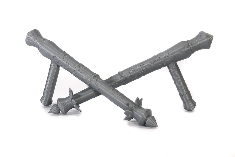 May include: Two gray, intricately designed, spiked maces with a handle on each side. The maces are crossed over each other.