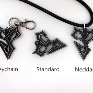 May include: Three versions of a black metal pendant with a stylized design. The pendant is shown as a keychain, a standard pendant, and a necklace.