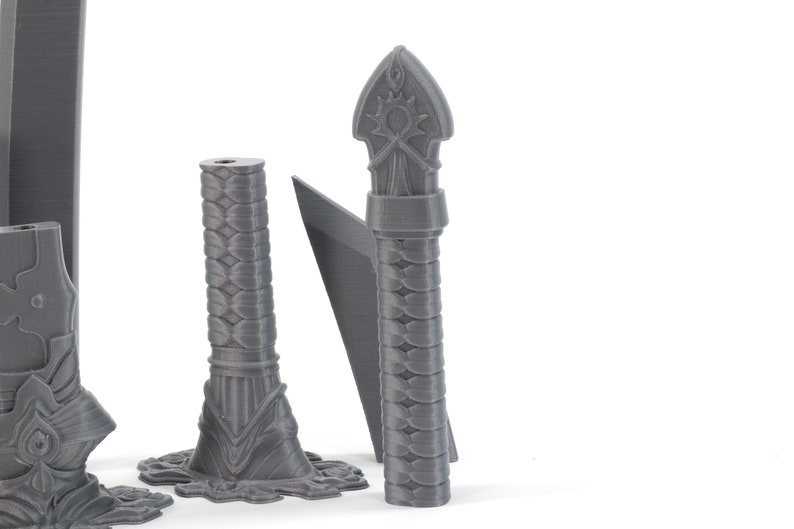 May include: Four grey 3D printed sword handles with intricate designs. The handles are made of a textured plastic material and have a variety of shapes and sizes.