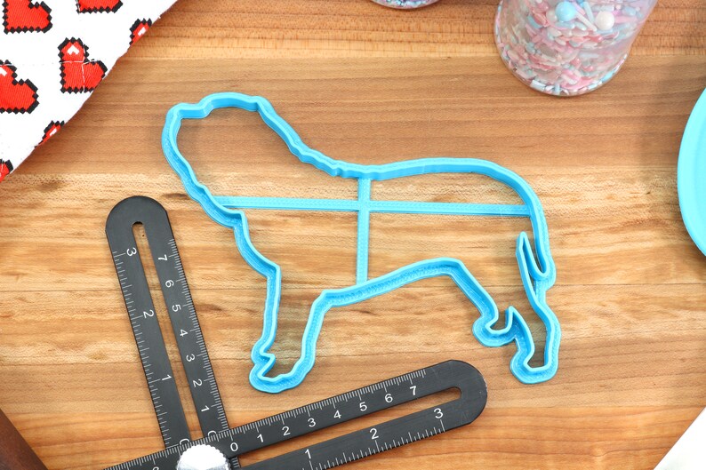 Peut inclure: Un emporte-pi&egrave;ce en plastique bleu en forme de chien. L'emporte-pi&egrave;ce est sur une surface en bois avec une r&egrave;gle &agrave; c&ocirc;t&eacute;.