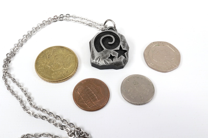 May include: A silver necklace with a pendant featuring a stylized spiral and stars. The pendant is about the size of a US quarter.