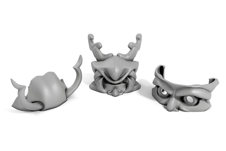 May include: Three gray plastic masks with different designs. The masks are all in the shape of a face, with different features such as horns, teeth, and eyes.