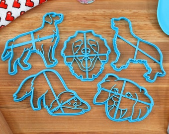 May include: Set of five blue plastic dog-shaped cookie cutters. The cutters are in the shape of a dog's head, a dog lying down, and three different standing dogs.