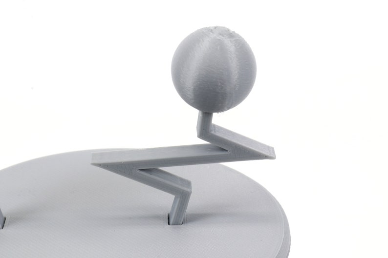 Pode incluir: Um modelo 3D impresso em cinza de um planeta em um suporte. O planeta &eacute; uma esfera com uma superf&iacute;cie texturizada. O suporte tem a forma de um ziguezague com uma base circular.