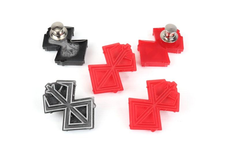 May include: Four pinback buttons with a geometric design. Two buttons are red and two buttons are black.