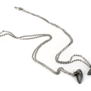 May include: A silver chain necklace with two silver heart pendants. The hearts have a textured surface with small holes.
