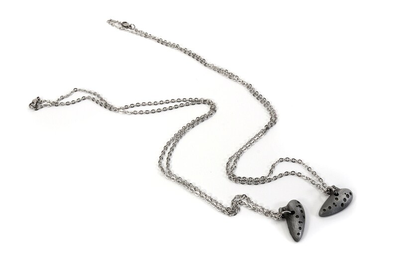 May include: A silver chain necklace with two silver heart pendants. The hearts have a textured surface with small holes.