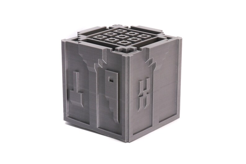 May include: A gray 3D printed cube with a grid pattern on the top and a design on each side. The design on the front side is a stylized letter "H".