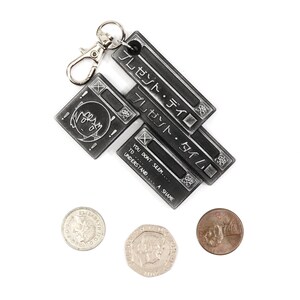 May include: A silver keychain with three metal tags. The top tag says "プレゼント・タイム" in Japanese. The middle tag says "プレゼント・タイム" in Japanese. The bottom tag says "YOU DON'T SEEM... TO... UNDERSTAND... A SHAME".