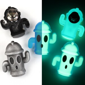 May include: Four fire hydrant-shaped pins, two are silver, one is blue, and one is glowing green in the dark. The pins have a cartoon face with two eyes and a surprised expression.