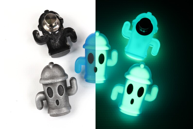 May include: Four fire hydrant-shaped pins, two are silver, one is blue, and one is glowing green in the dark. The pins have a cartoon face with two eyes and a surprised expression.