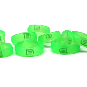 May include: A group of ten green silicone rings with a raised logo of three horizontal lines. The rings are stacked and scattered on a white background.