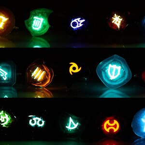 May include: A set of 15 glowing resin dice with various symbols and colours, including blue, green, orange, and red. The dice are arranged in three rows of five.