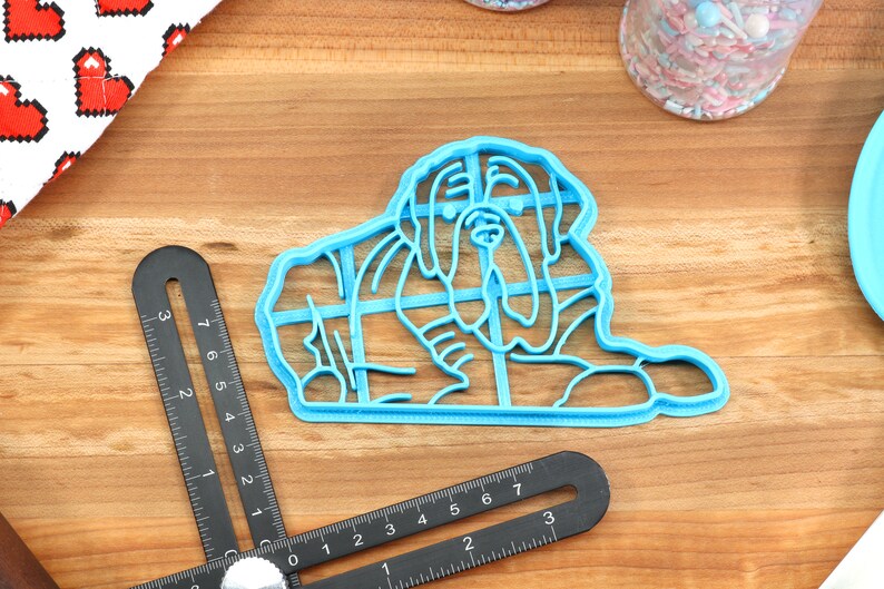 Peut inclure: Un emporte-pi&egrave;ce en plastique bleu en forme de chien, pos&eacute; sur une surface en bois.