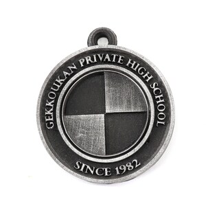 May include: A silver-colored metal keychain with the words "Gekkoukan Private High School Since 1982" around a black and white checkered circle.