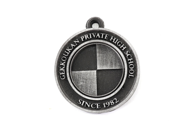 May include: A silver-colored metal keychain with the words "Gekkoukan Private High School Since 1982" around a black and white checkered circle.