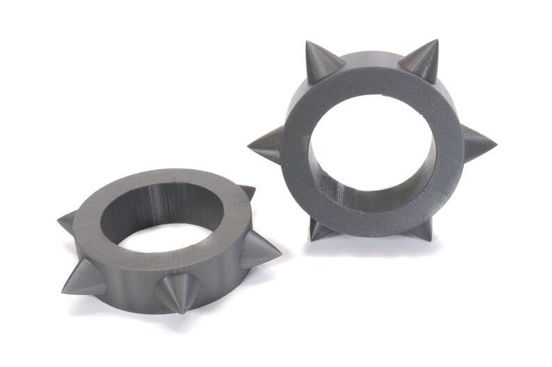 May include: Two grey, 3D printed rings with sharp, pointed spikes around the circumference.