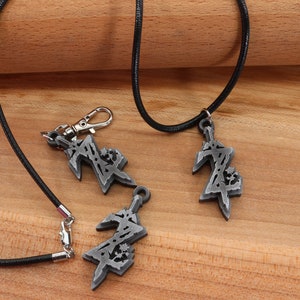 May include: Three silver pendants with a stylized design, two on black cords and one on a silver chain. The pendants are in the shape of a sword with a stylized design.