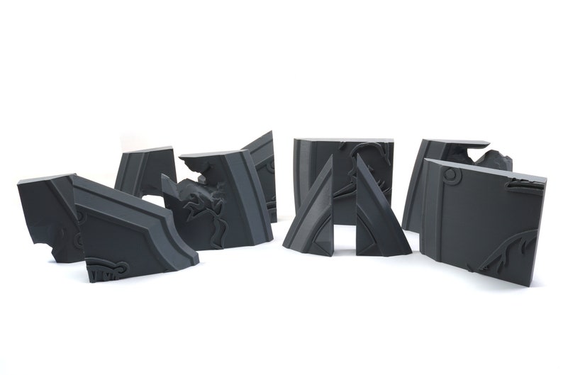 May include: A set of six gray, intricately detailed, 3D printed puzzle pieces. The pieces are shaped like geometric blocks with a variety of angles and curves. The pieces are designed to fit together to form a larger structure.