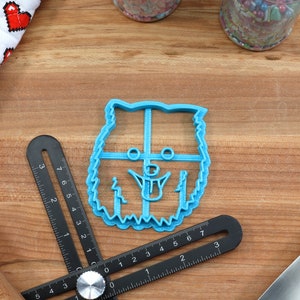 May include: A blue plastic cookie cutter shaped like a dog's head. The cutter has a detailed design with a tongue sticking out.
