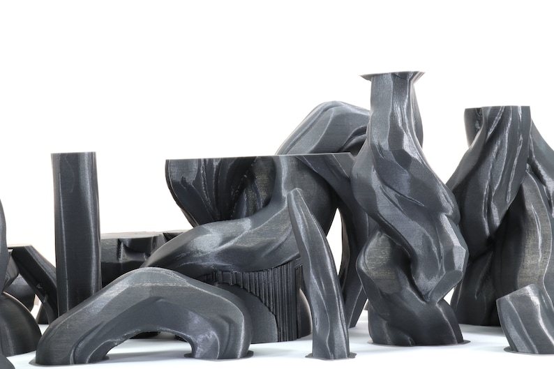 Puede incluir: Una colecci&oacute;n de esculturas abstractas impresas en 3D de color gris con una superficie lisa y texturizada. Las esculturas est&aacute;n dispuestas en un grupo, creando una exhibici&oacute;n moderna y art&iacute;stica.