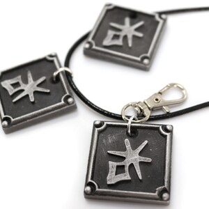 May include: A black necklace with three silver square pendants. Each pendant has a silver kanji character on a black background.