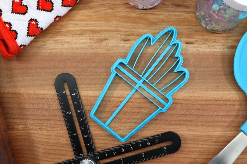 K&ouml;nnte beinhalten: Ein blauer Plastik-Ausstecher in Form einer Topfpflanze. Der Ausstecher hat ein detailliertes Design mit mehreren Bl&auml;ttern und einem Topf.