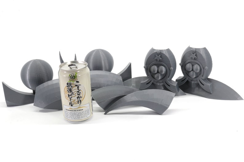 May include: A gray 3D printed model of a robot with a can of Japanese beer in the foreground. The robot has a star on its chest and a circular design on its head. The beer can has Japanese text and the words "Japanese Craft Liquor" printed on it.