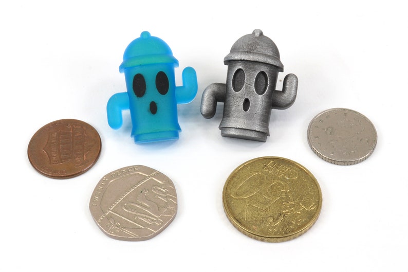 May include: Two small fire hydrant figurines, one blue and one silver, with a surprised expression on their faces. The figurines are sitting on a white surface with four coins.