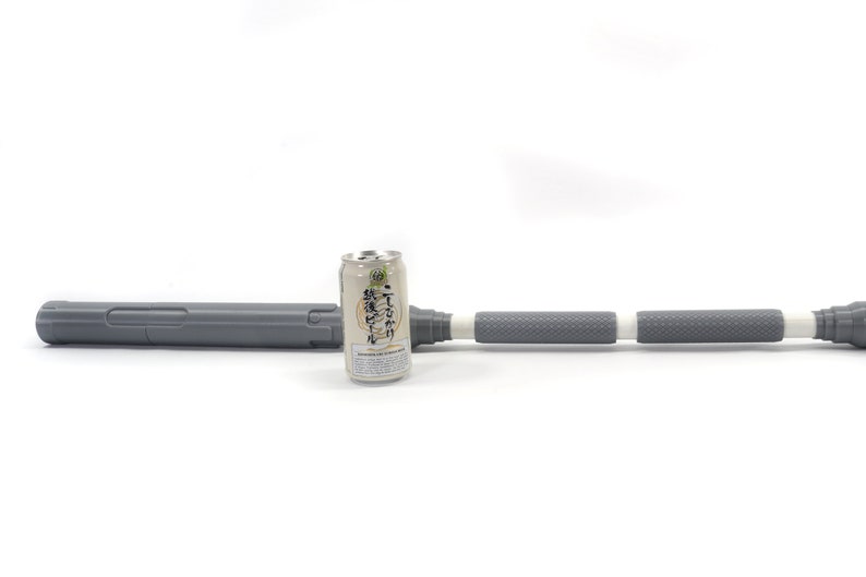 K&ouml;nnte beinhalten: Ein grauer Teleskopschlagstock mit einem wei&szlig;en Griff und einem schwarzen Etikett auf der Dose. Die Dose ist mit japanischem Text beschriftet.