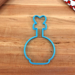 May include: Blue plastic cookie cutter shaped like a bottle with a heart-shaped top.