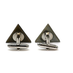 May include: A pair of silver cufflinks with a triangular green and black design.