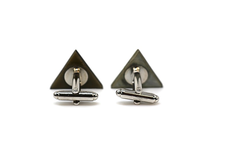 May include: A pair of silver cufflinks with a triangular green and black design.